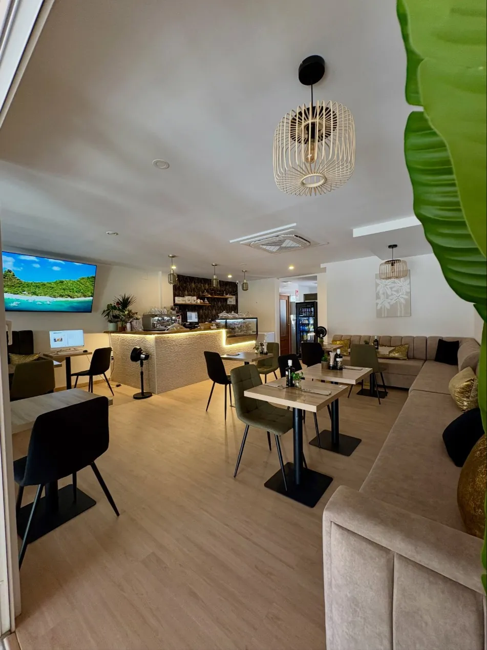 Salón de Golden Brunch con sofás beige, lámparas de ratán y la barra iluminada